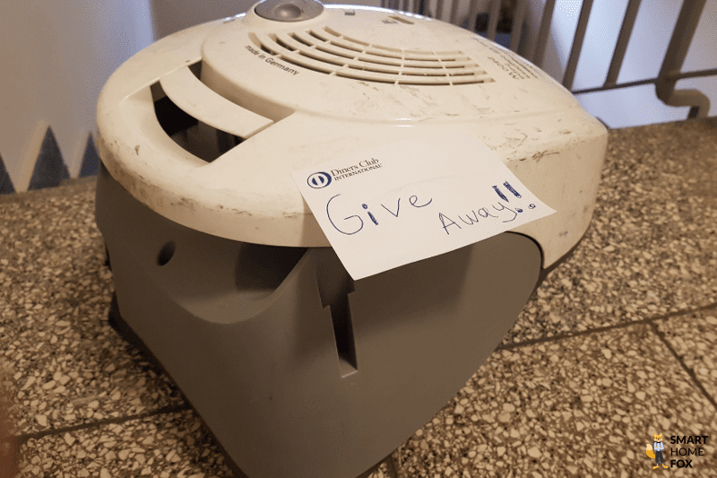 Ein alter Staubsauger mit einer handgeschriebenen Notiz steht im Treppenhaus zum Verschenken